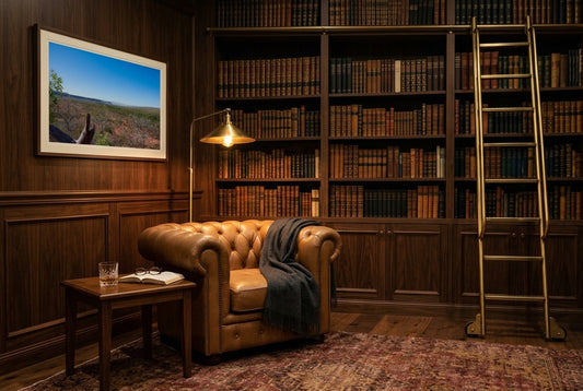Kimberley Horizon — El Questro Lookout, framed in a literary library reading corner — leather Chesterfield armchair, floor-to-ceiling timber bookshelves, rolling library ladder, brass library lamp, dark wood frame. — Two Fat Bunnies.