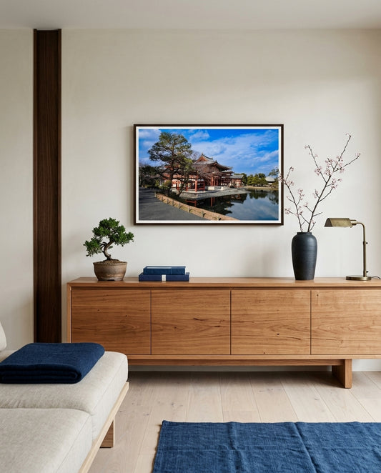 Timeless Serenity: View of the Phoenix Hall, Byōdō-in, framed above a blackbutt sideboard in a Kyoto-modern living room — raw timber wall, low linen sofa, paper floor lamp, ceramic vessel, dark wood frame. — Two Fat Bunnies.
