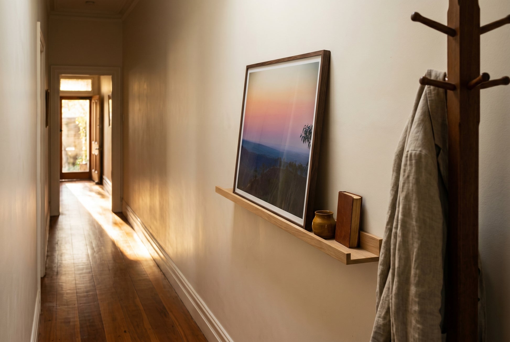 Afterglow over El Questro, Pastel Twilight from Buddy's Lookout, propped on a slim oak picture ledge in a Melbourne terrace hallway — patterned runner, dark spotted gum floor, ceramic vessel, book stop, dark wood frame. — Two Fat Bunnies.