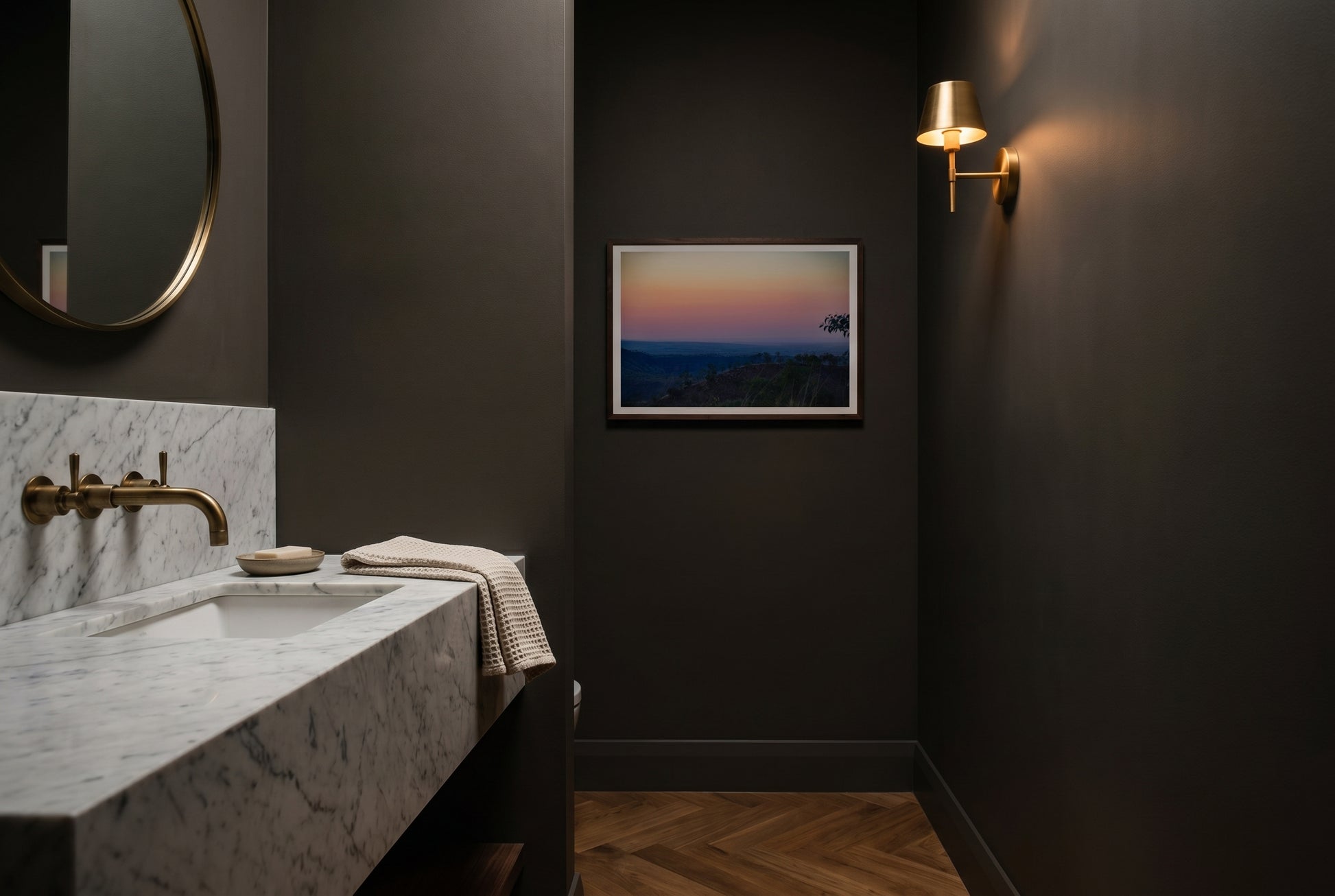 Afterglow over El Questro, Pastel Twilight from Buddy's Lookout, framed as the sole artwork in a heritage Australian powder room — Carrara marble vanity, antique brass tap, deep mushroom-charcoal walls, warm sconce, dark wood frame. — Two Fat Bunnies.