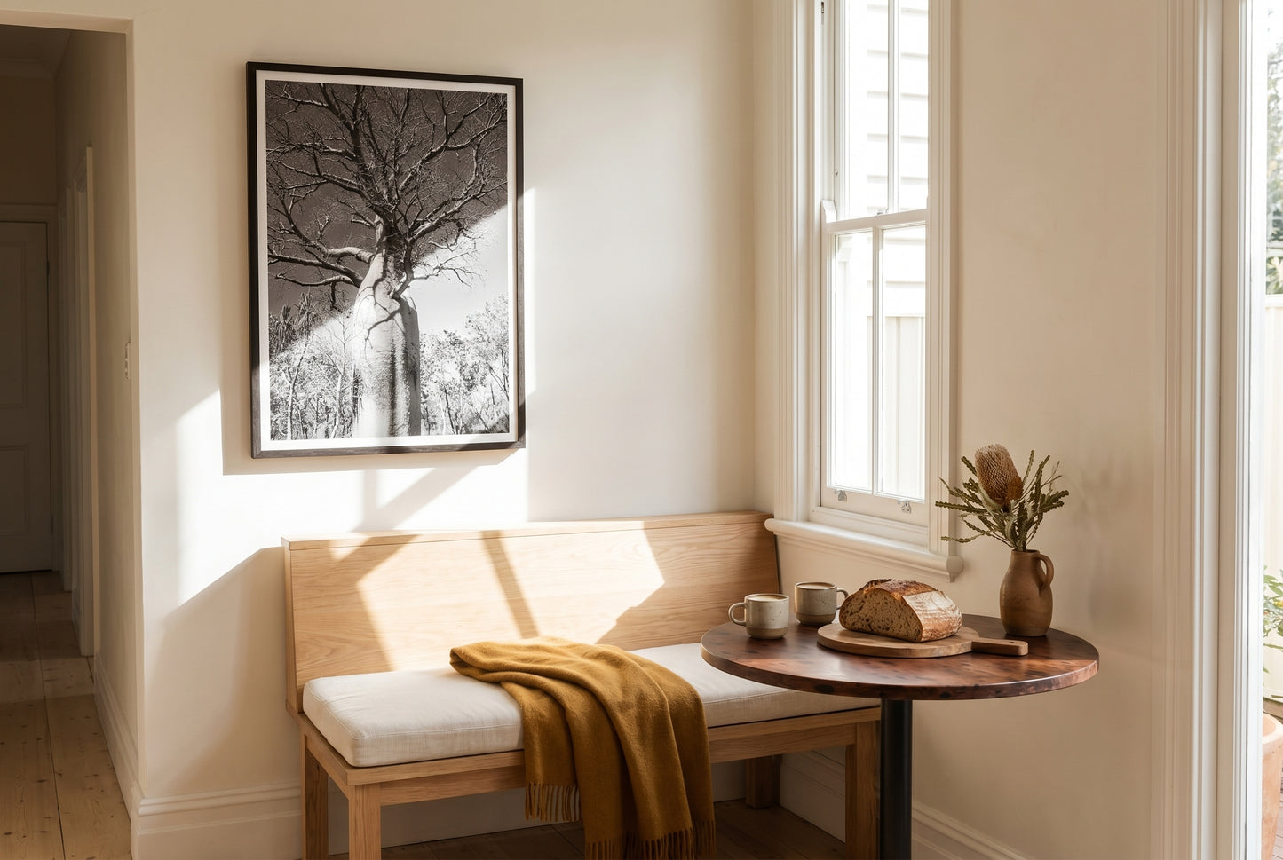 Ancient Sentinel — El Questro Boab, framed above a small built-in oak banquette in a warm Australian kitchen breakfast nook — sash window, sourdough on board, dark wood frame. — Two Fat Bunnies.