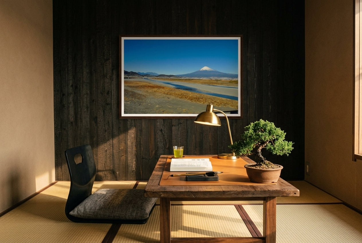 Mt Fuji and the Arched Bridge — Shinkansen View, framed on a dark cedar feature wall above a low aged-walnut writing desk in a Tokyo apartment-inspired writing study — tatami, brass desk lamp, ink stone, bonsai juniper, dark wood frame. — Two Fat Bunnies.