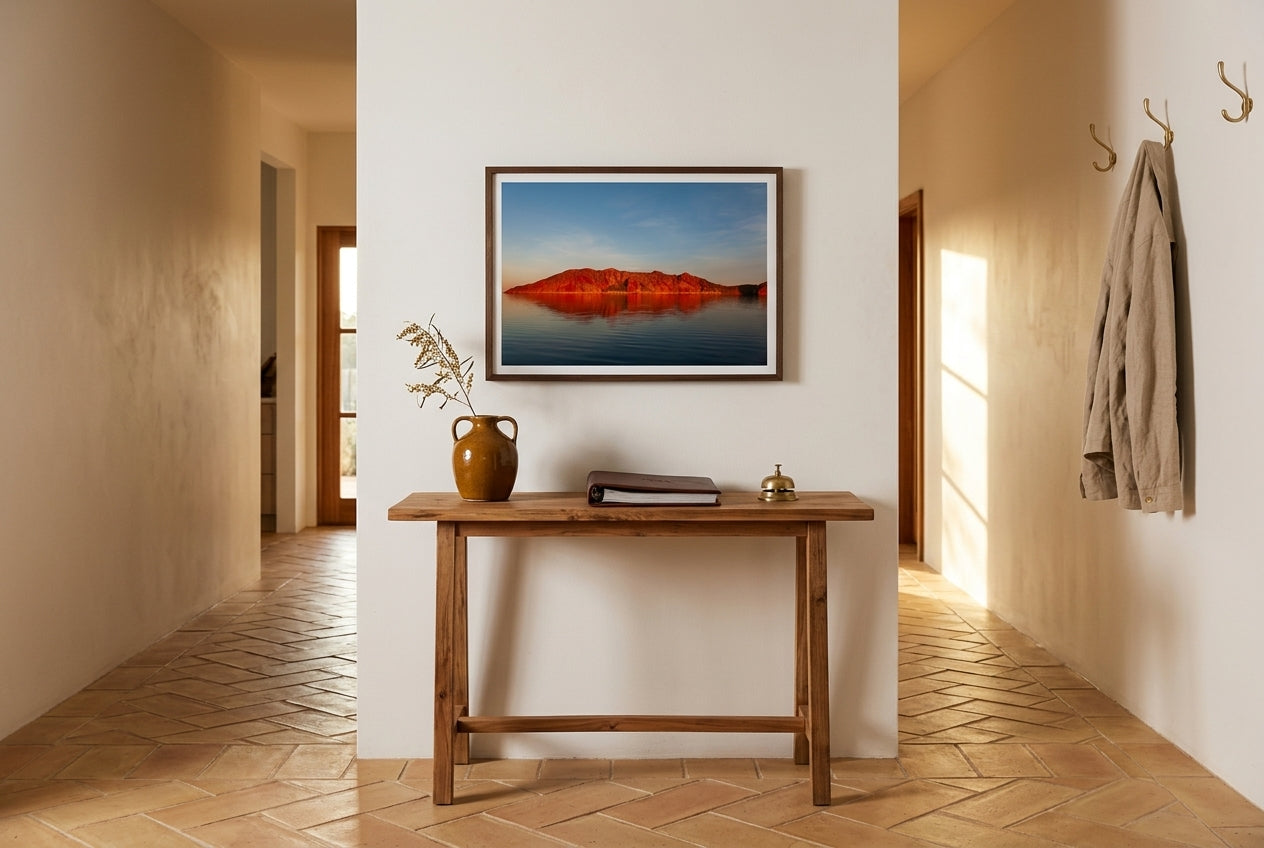 Crimson Calm — Island Before Sunset, Lake Argyle, framed above a slim cedar console in a contemporary Australian hallway — honey terracotta tile, dried wattle, brass coat hooks, dark wood frame. — Two Fat Bunnies.
