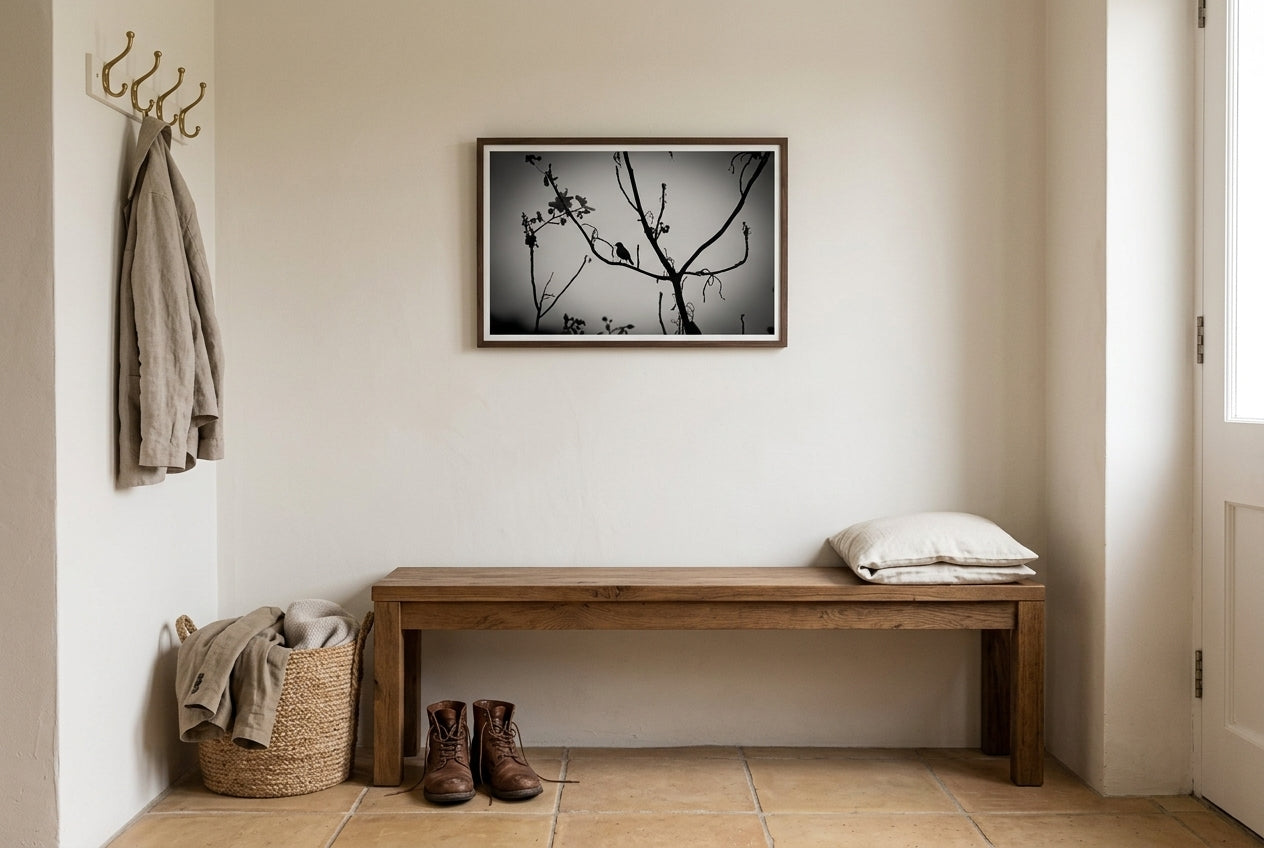 Dusk Solitude — El Questro Bird Silhouette, framed above a low recycled-timber bench in a peaceful entry vestibule — cream linen cushion, leather boots, jute basket, honey terracotta tile, dark wood frame. — Two Fat Bunnies.