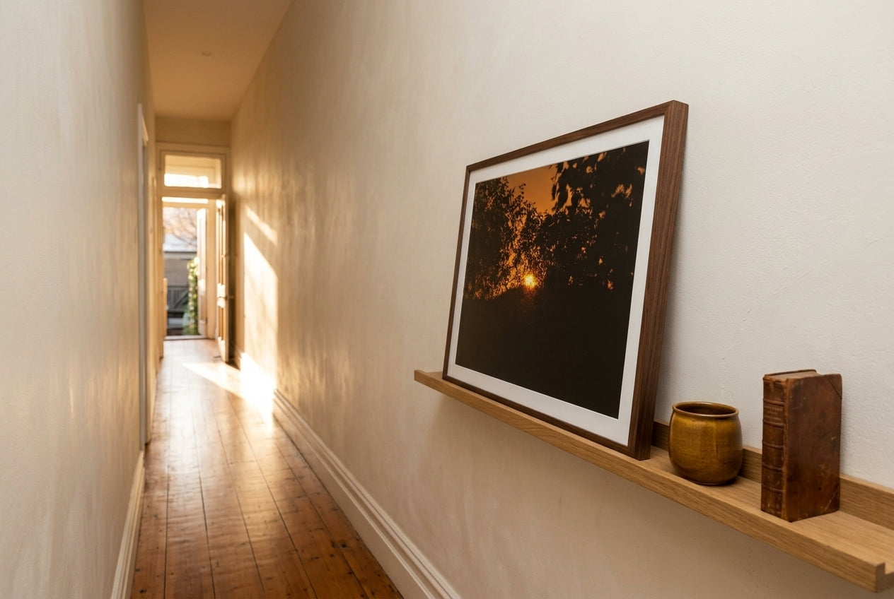Ember Set at Buddy's Lookout, El Questro, propped on a slim oak picture ledge in a Melbourne terrace hallway — patterned ochre runner, dark spotted gum floor, ceramic vessel, book stop, dark wood frame. — Two Fat Bunnies.