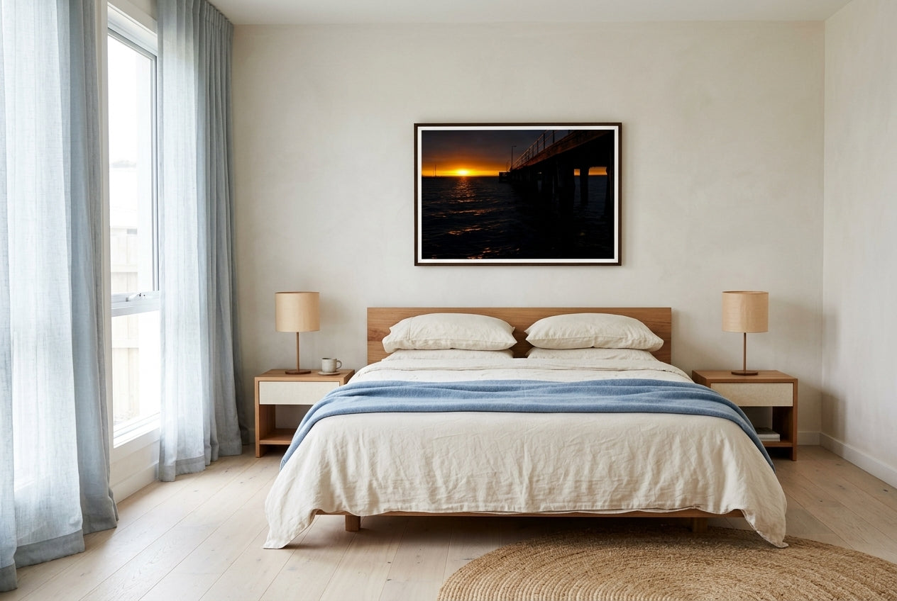 Flinders Sunrise Glow, framed above the headboard of a blackbutt platform bed in a coastal-Japandi master bedroom — cream linen bedding, paper lamp, dark wood frame. — Two Fat Bunnies.