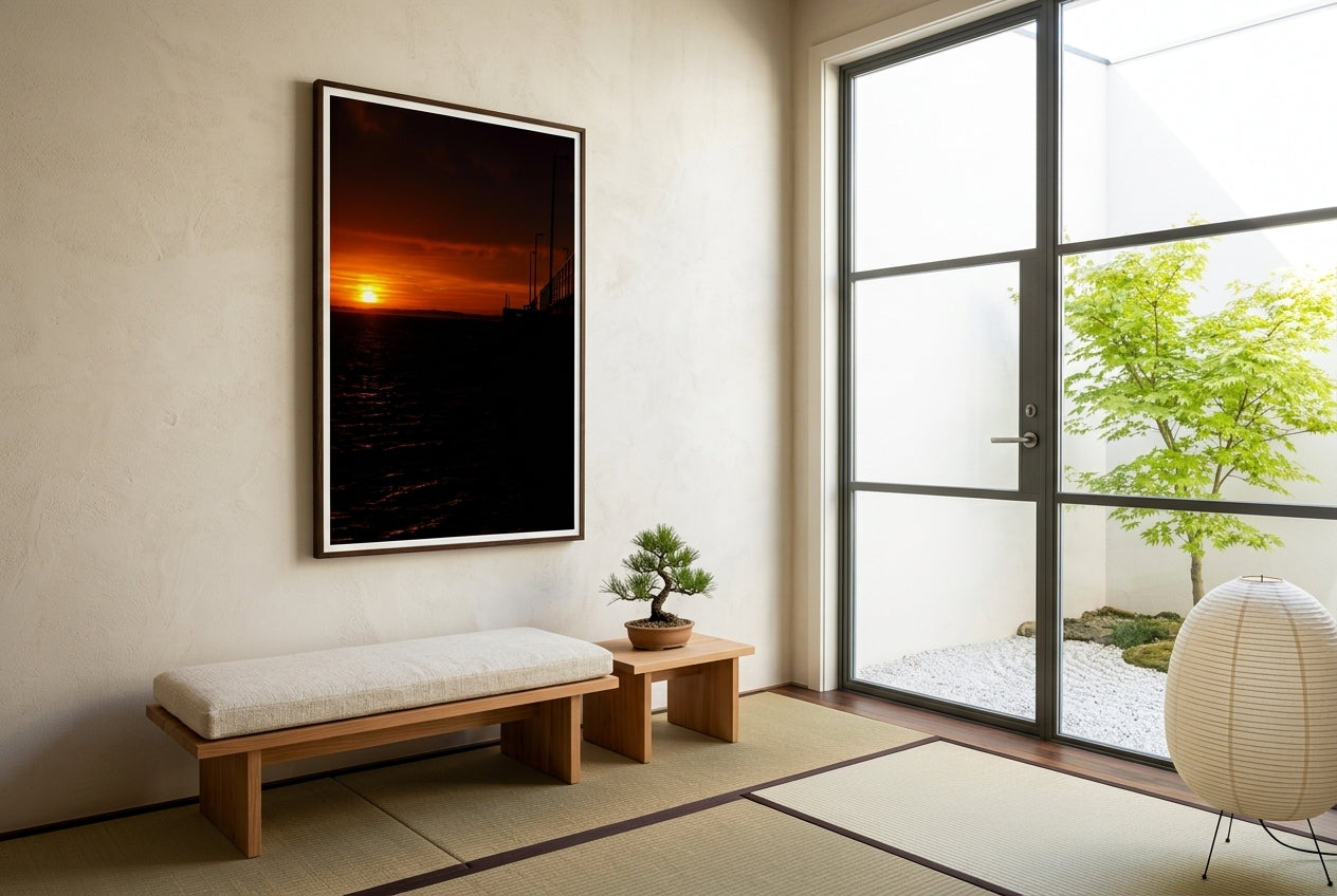 Golden Dawn at Flinders Pier, framed in a Japanese-inspired garden room — steel-framed glass door onto a dry-stone garden, low cedar bench, bonsai pine, paper lantern, dark wood frame. — Two Fat Bunnies.