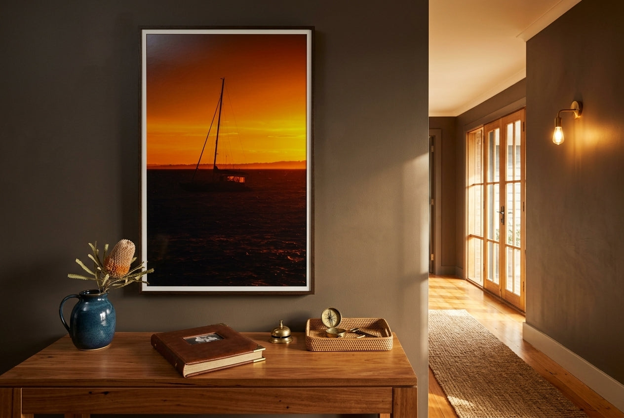 Golden Dawn at Flinders – Sunrise Boat, framed above a generous blackbutt console in a Mornington heritage entry hall — deep mushroom plaster, coastal-blue ceramic, polished blackbutt floors, brass sconce, dark wood frame. — Two Fat Bunnies.