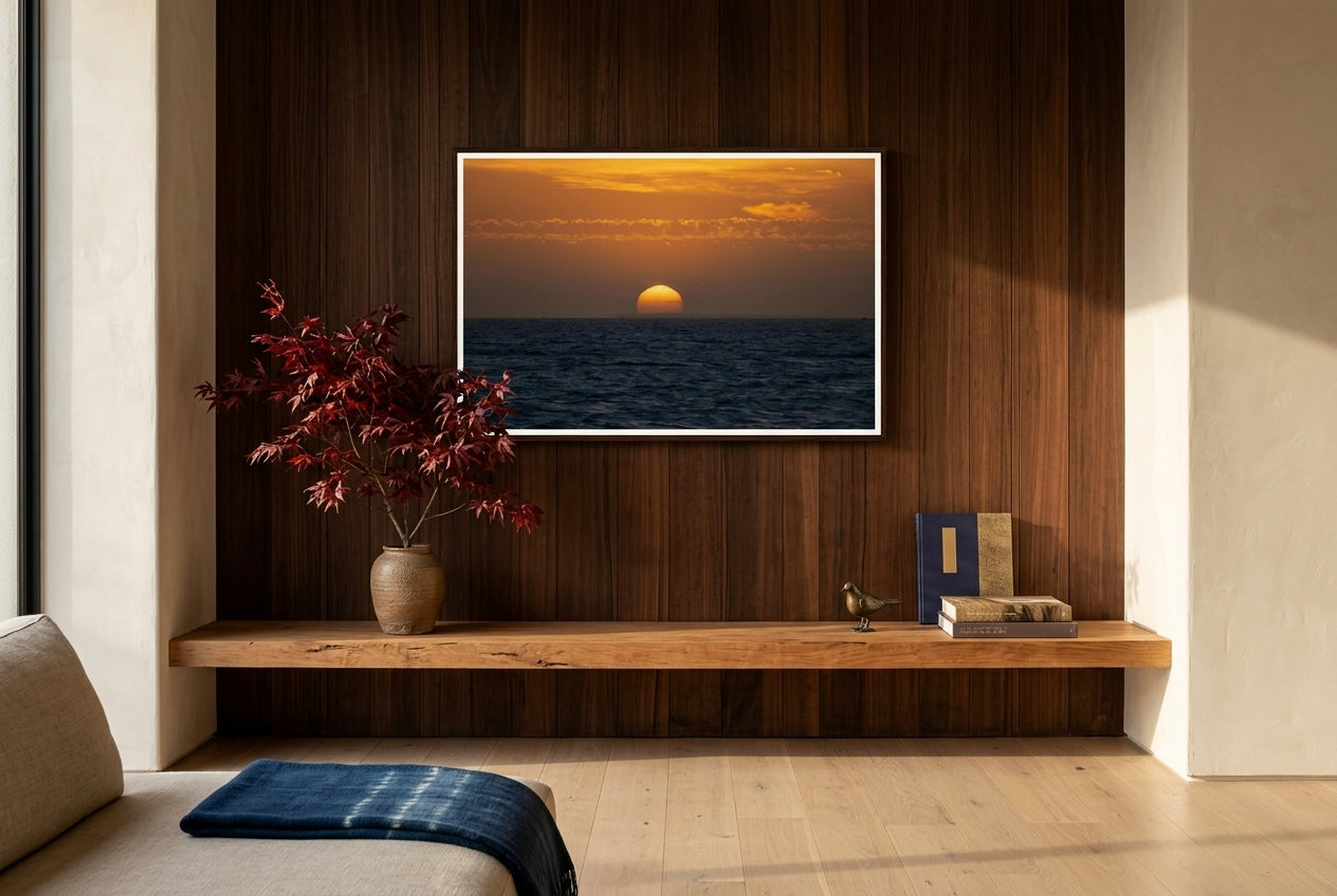 Golden Dusk: Sunset Over Port Phillip Bay, Melbourne, framed above a low cedar mantel-console in an Australian-Japanese fusion living room — ikebana, cedar feature wall, oat linen sofa, dark wood frame. — Two Fat Bunnies.