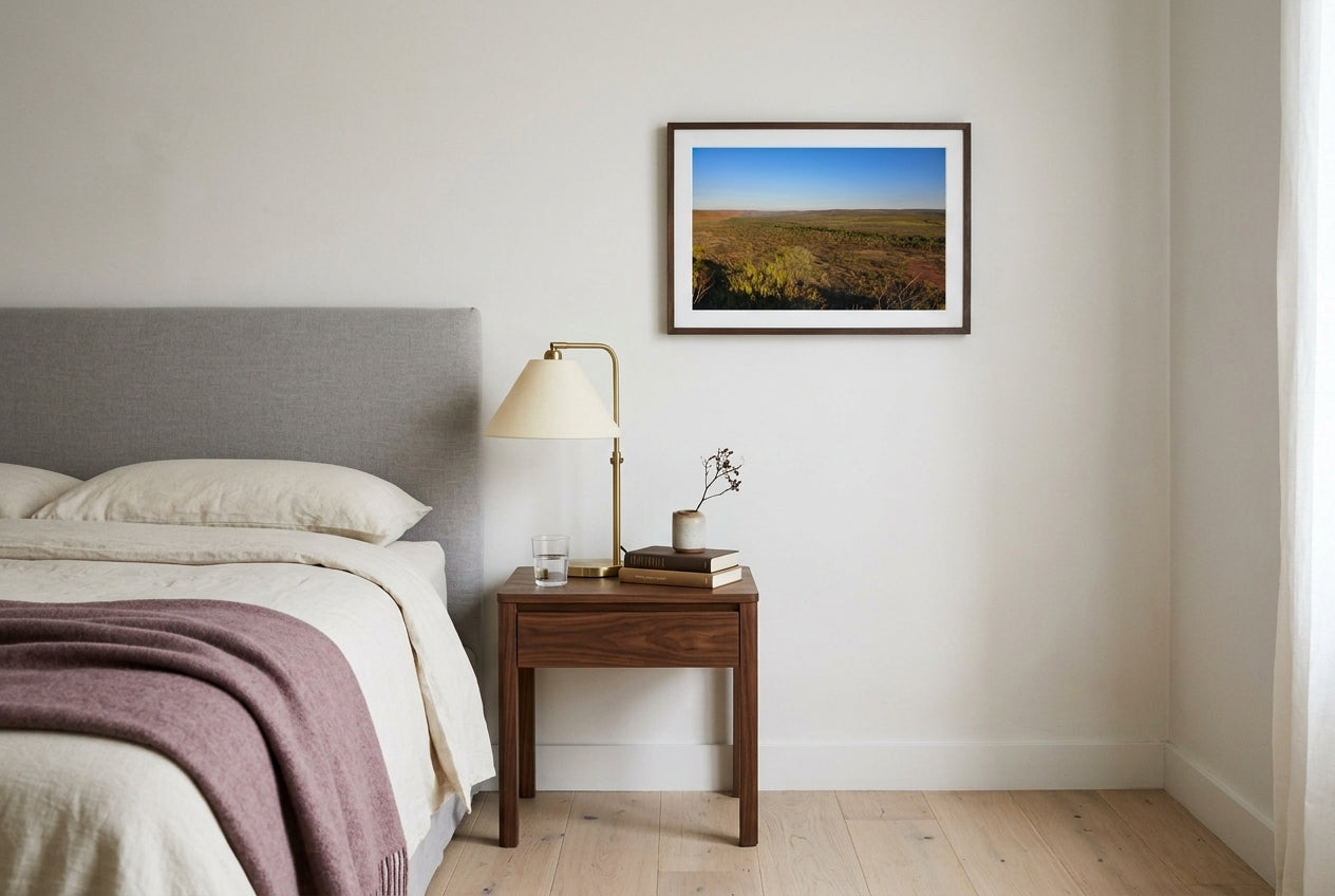 Golden Hour Across El Questro, Buddy's Lookout, framed above a walnut bedside table in a small Melbourne bedroom — dove-grey headboard, brass reading lamp, dark wood frame. — Two Fat Bunnies.