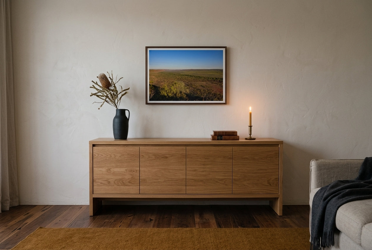 Golden Hour Across El Questro, Buddy's Lookout, framed above a low oak sideboard in a contemplative Australian living room — charcoal ceramic vessel, dried banksia, brass candle, dark wood frame. — Two Fat Bunnies.