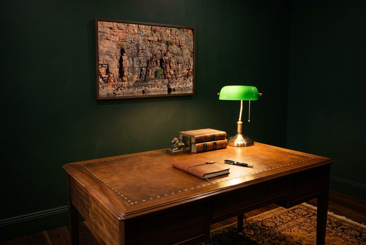 Golden Strata, Chamberlain Gorge, framed above a polished walnut desk in a lawyer's home office — brass banker's lamp, leather-bound legal volumes, deep British-racing-green walls, dark wood frame. — Two Fat Bunnies.