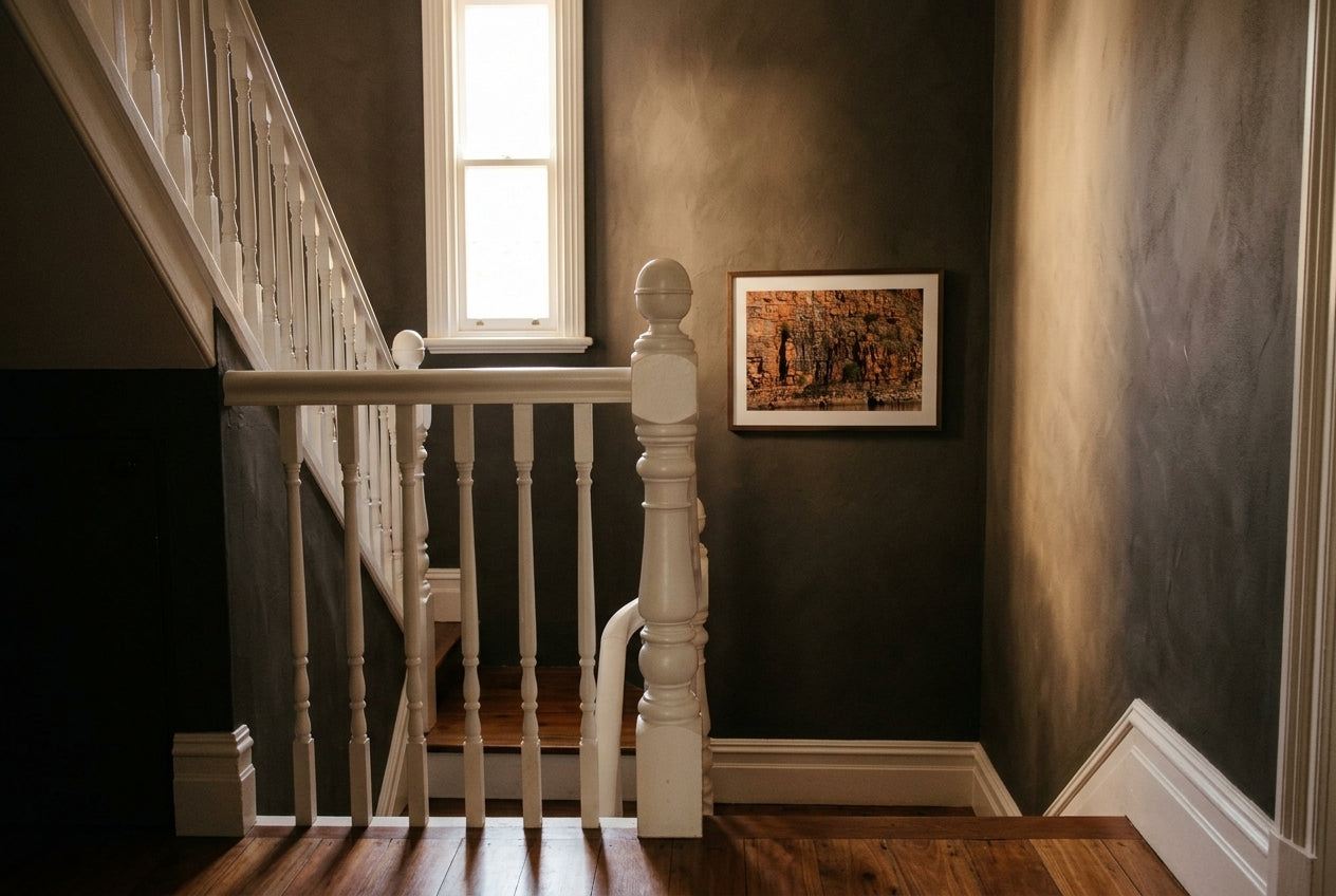 Golden Strata, Chamberlain Gorge, framed as the single artwork on a heritage Australian stairwell landing — mushroom-charcoal plaster, high sash window, polished timber handrail, dark wood frame. — Two Fat Bunnies.
