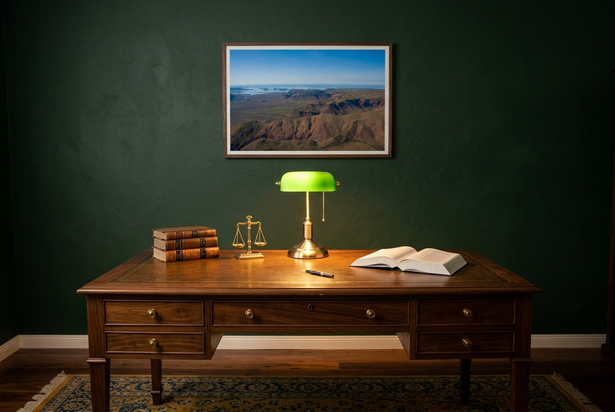 Lake Argyle From Above, framed above a polished walnut desk in a lawyer's home office — brass banker's lamp, leather-bound legal volumes, deep British-racing-green walls, dark wood frame. — Two Fat Bunnies.