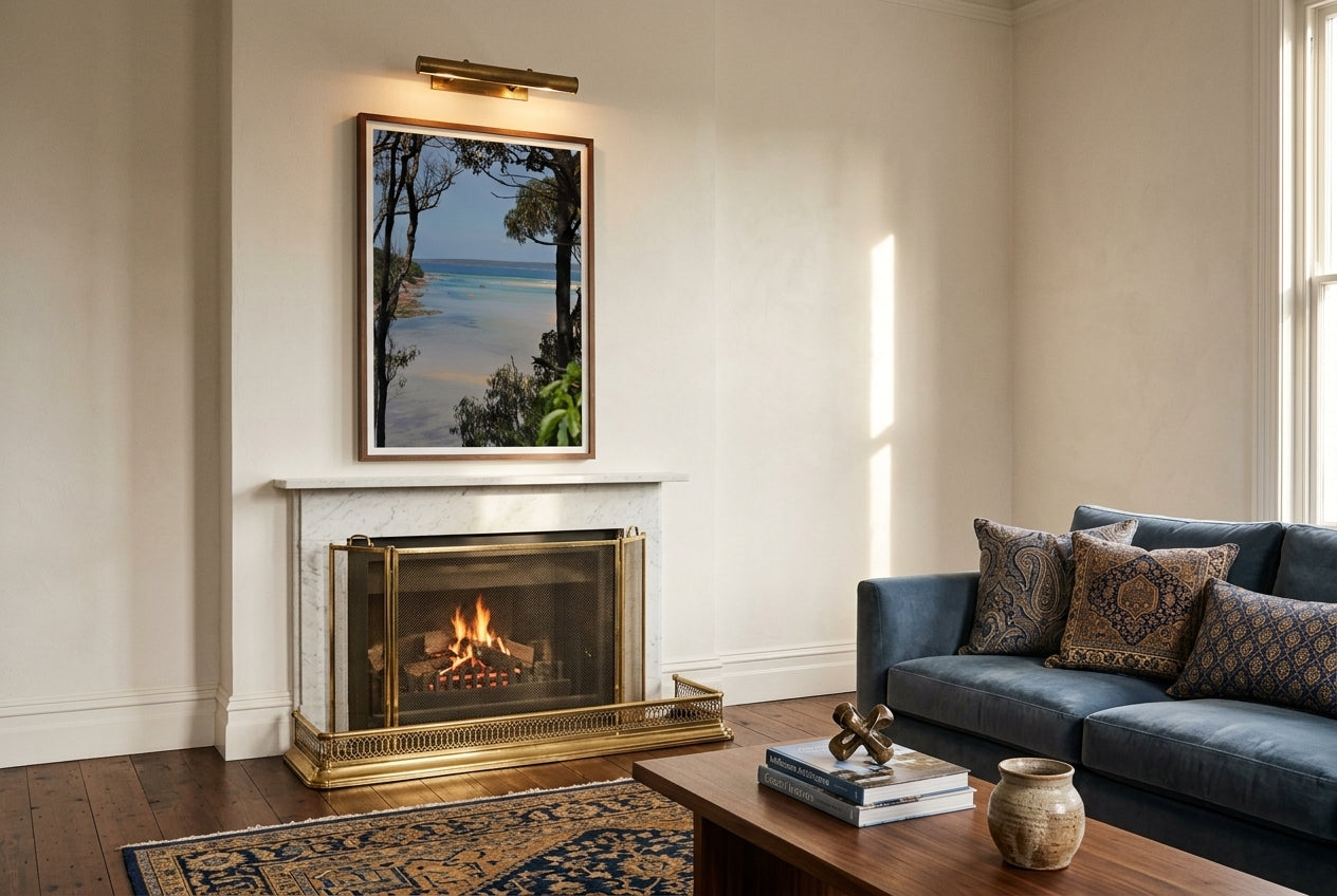 Merimbula Bliss, framed above a formal living room fireplace — white-marble mantel, brass fender, deep velvet sofa, oriental rug, dark wood frame. — Two Fat Bunnies.