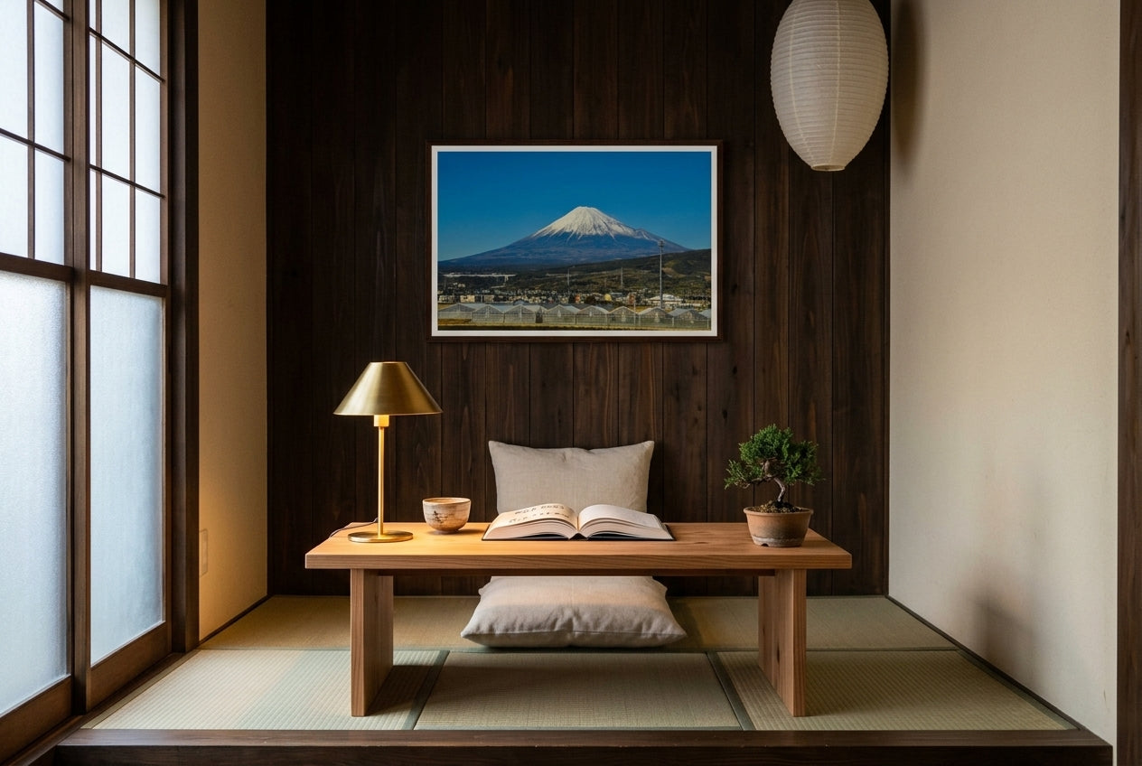Mt Fuji in Motion: Shinkansen View, framed above a low cedar reading desk in a Japanese-modern reading corner — raised tatami, zabuton cushion, brass paper lamp, bonsai juniper, dark wood frame. — Two Fat Bunnies.