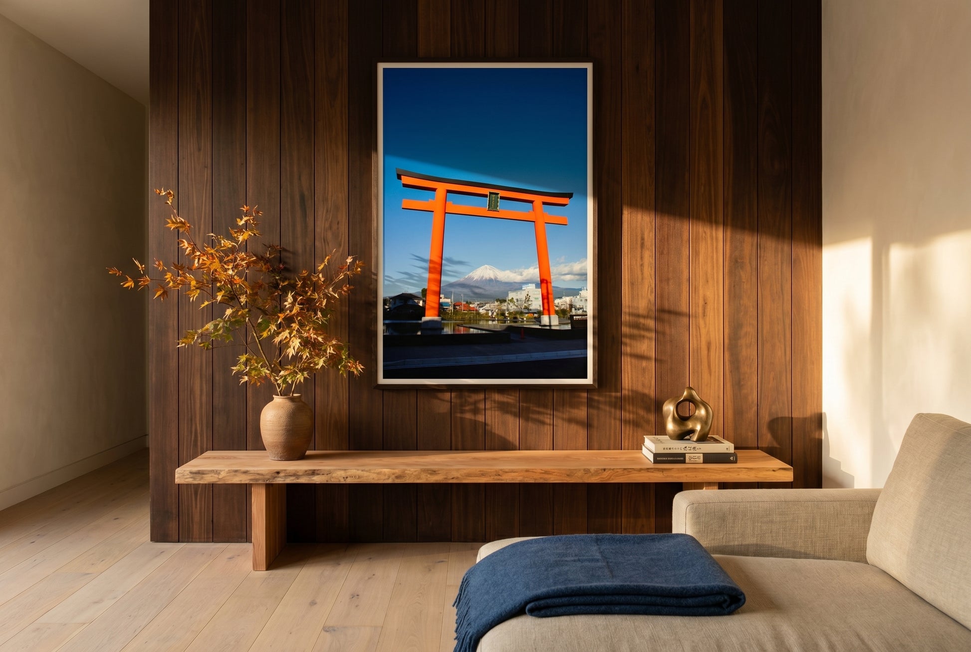 Mt Fuji Through the Torii Gate – Shizuoka, framed above a low cedar mantel-console in an Australian-Japanese fusion living room — cedar feature wall, ikebana arrangement, oat linen sofa, dark wood frame. — Two Fat Bunnies.