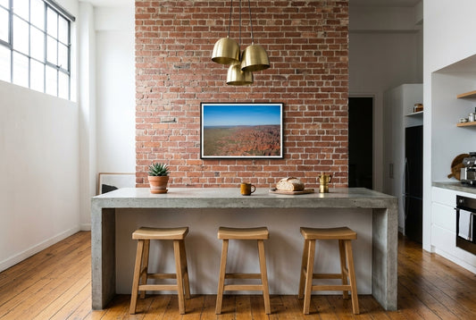 Over the Bungle Bungles, framed above the kitchen island in an urban Melbourne warehouse loft — polished concrete island, industrial steel-framed window, exposed timber beams, brass pendants, dark wood frame. — Two Fat Bunnies.