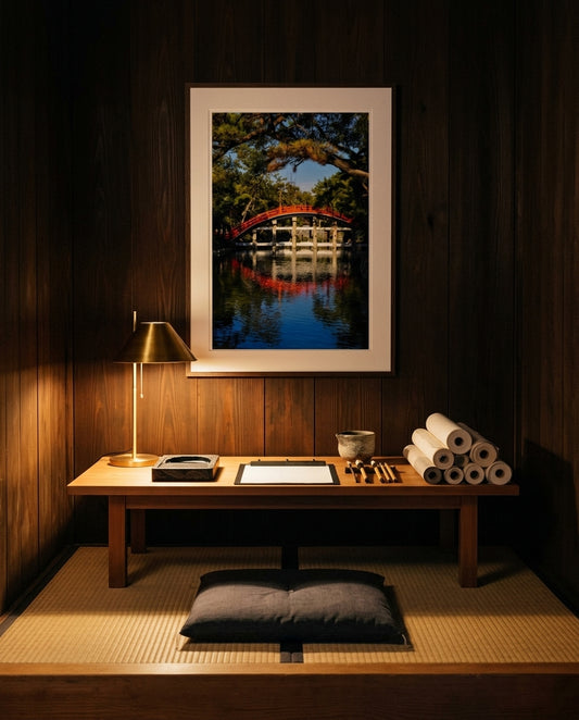 Sumiyoshi Taisha Bridge – Vibrant Japanese Shrine Art, framed above a low cedar chabudai writing desk in a calligrapher's atelier — ink stones, sumi brushes, washi paper roll, paper-shaded lamp, dark wood frame. — Two Fat Bunnies.