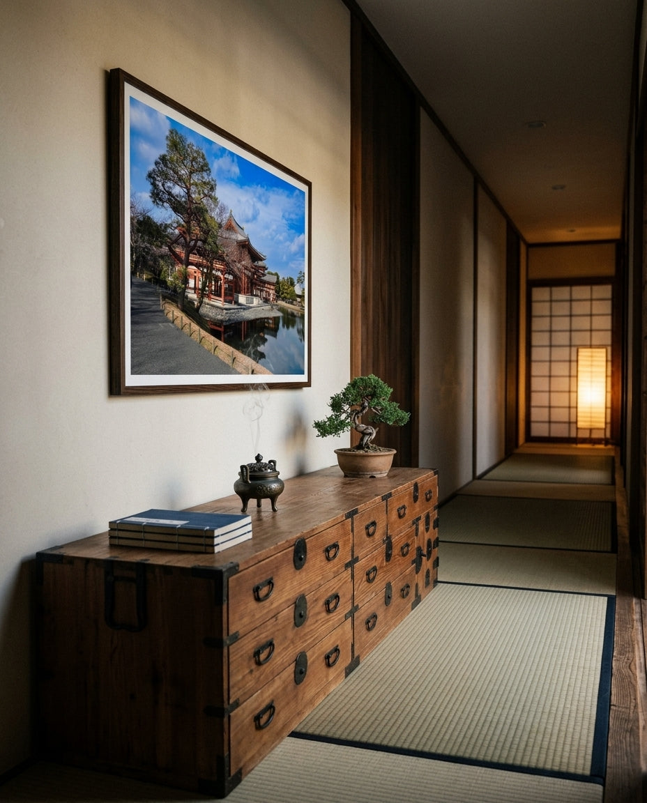 Timeless Serenity: View of the Phoenix Hall, Byōdō-in, framed above a tansu chest in a ryokan-inspired corridor — cedar walls, paper lamp, woven runner, ceramic bowl, dark wood frame. — Two Fat Bunnies.